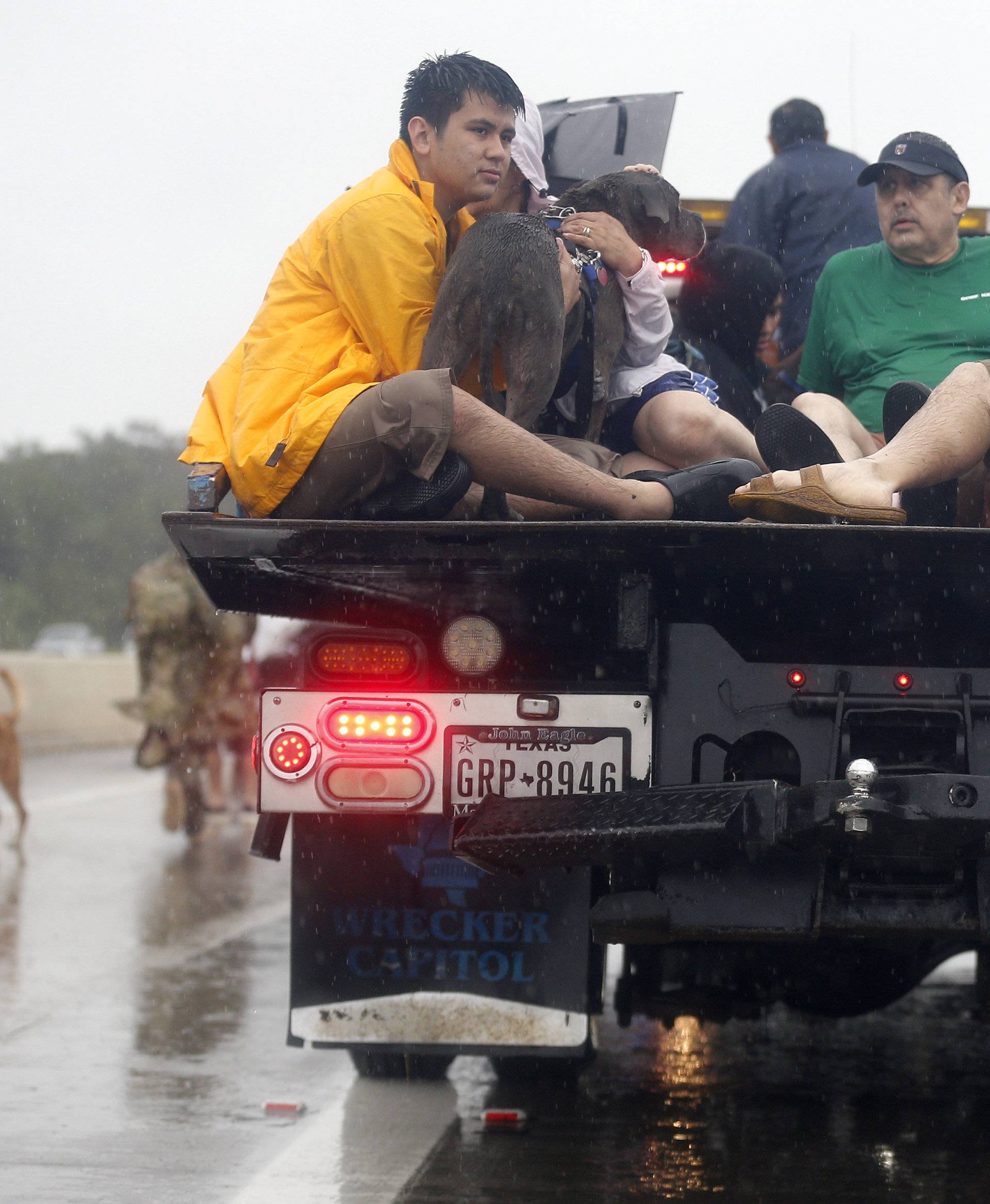 Residents sit on the bed of a tow truck after being rescued from the flood waters of tropical storm Harvey in east Houston