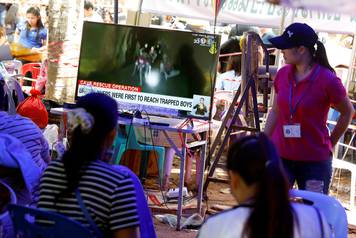 Family members watch a television news broadcast of the trapped members of an under-16 soccer team and their coach, after they have been reported by local media to be found alive, in Chiang Rai