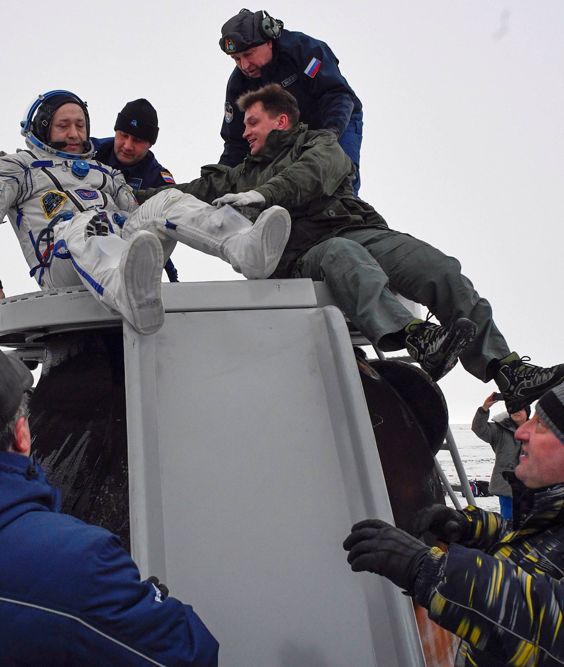 Ground personnel help Alexander Misurkin of Russia to get out of the Soyuz MS-06 space capsule after landing in a remote area outside the town of Dzhezkazgan
