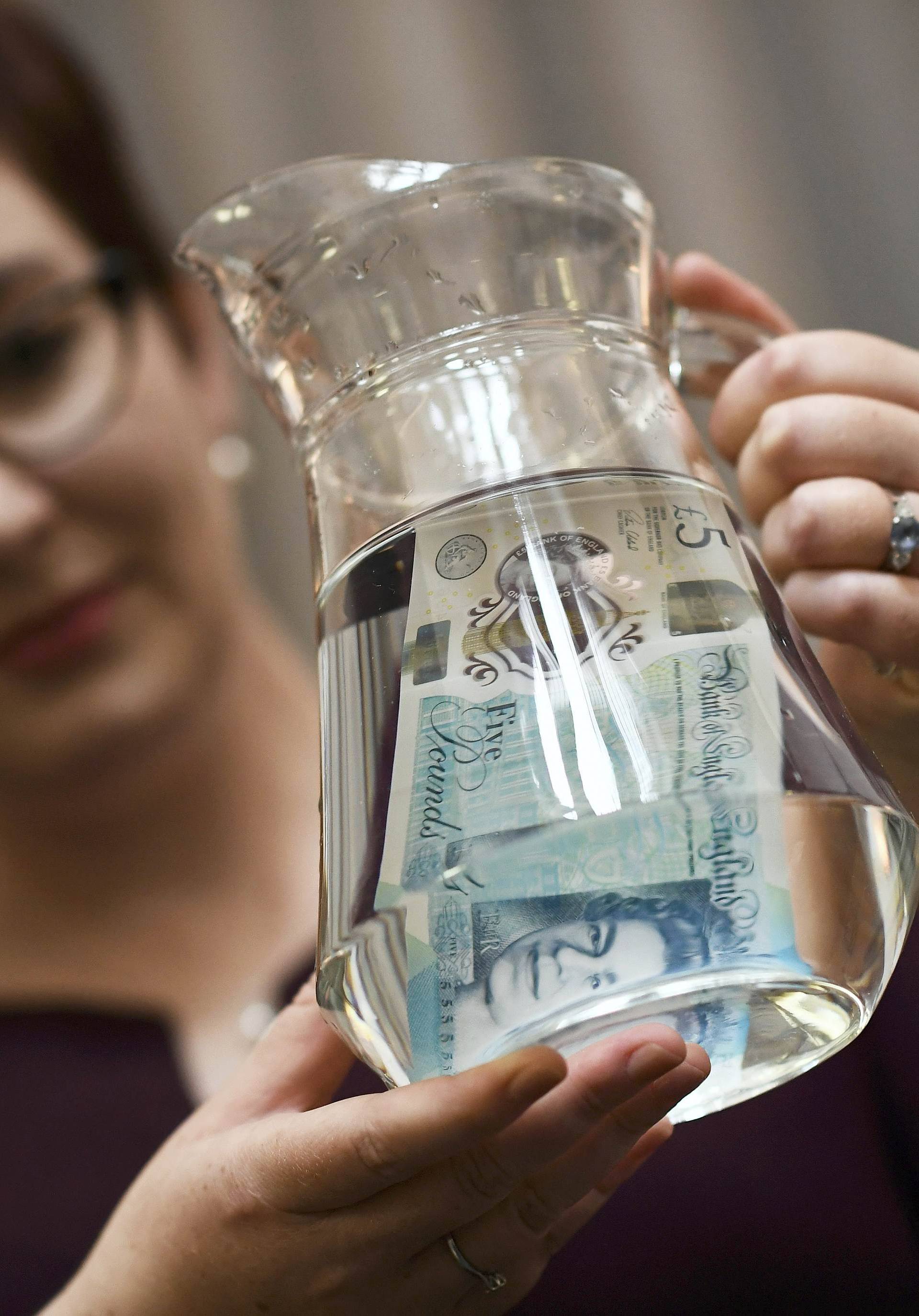 Bank of England Museum curator shows off the waterproof properties of the new polymer five pound note during an event at the Bank of England in London