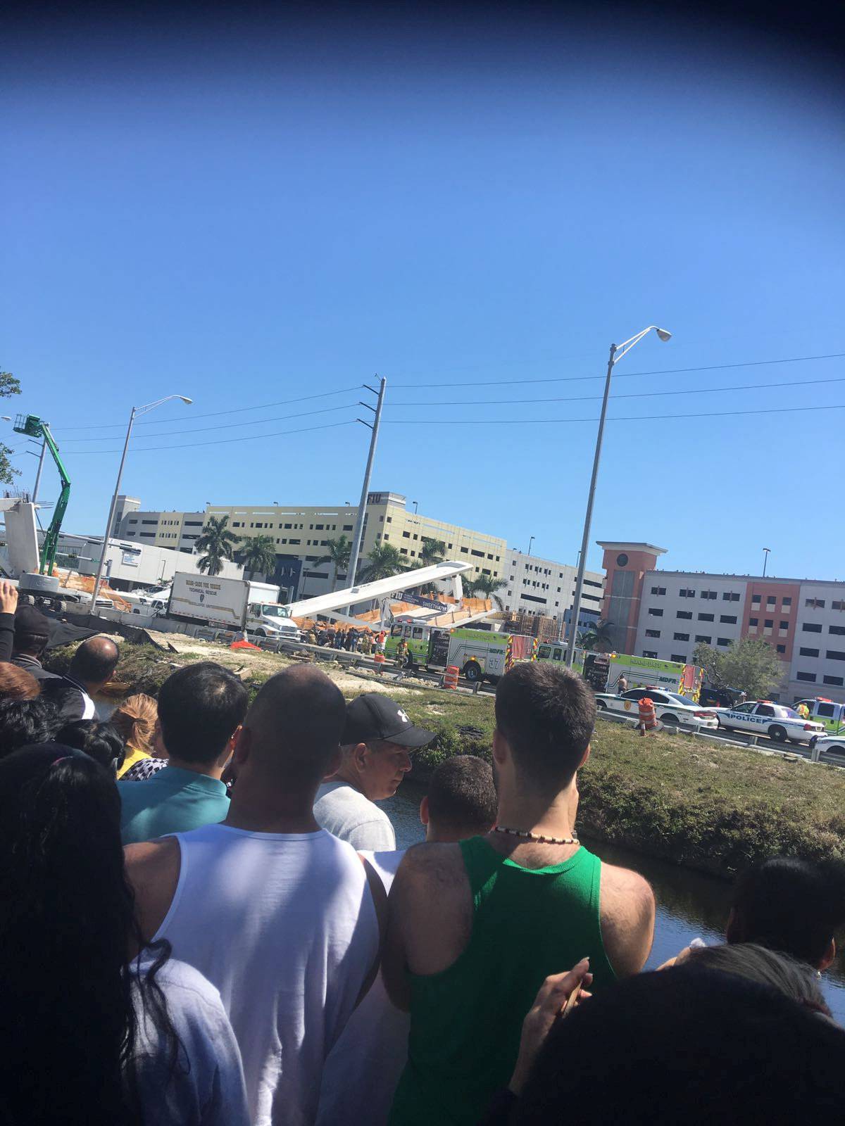 People view the scene of a collapsed pedestrian bridge at Florida International University in Miami