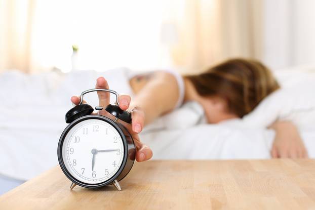 Sleepy,Young,Woman,Trying,Kill,Alarm,Clock,While,Bury,Face