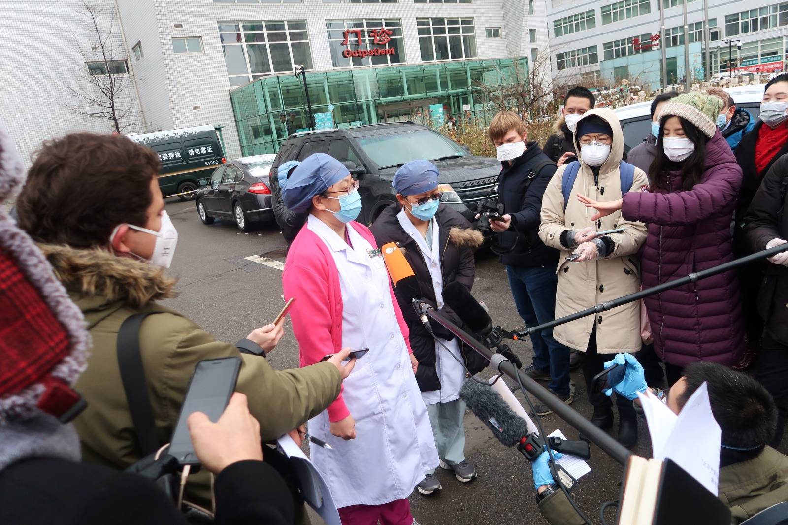 Medical workers wearing face masks speak to journalists outside a hospital where three patients cured of the novel coronavirus were discharged, in Beijing