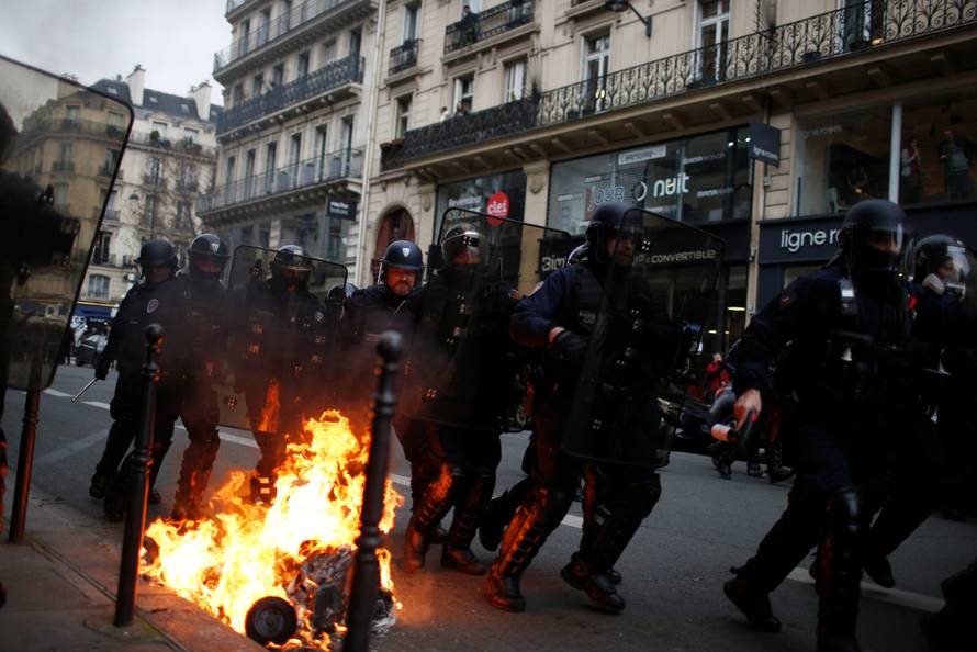 French riot police run in a street during clashes with protesters wearing yellow vests during a national day of protest by the "yellow vests" movement in Paris