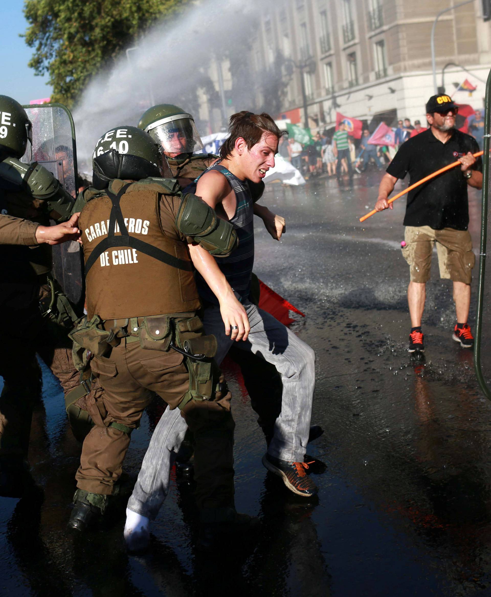 A demonstrator is detained by riot police during a rally in defense of the nationalization of lithium reserves in Santiago