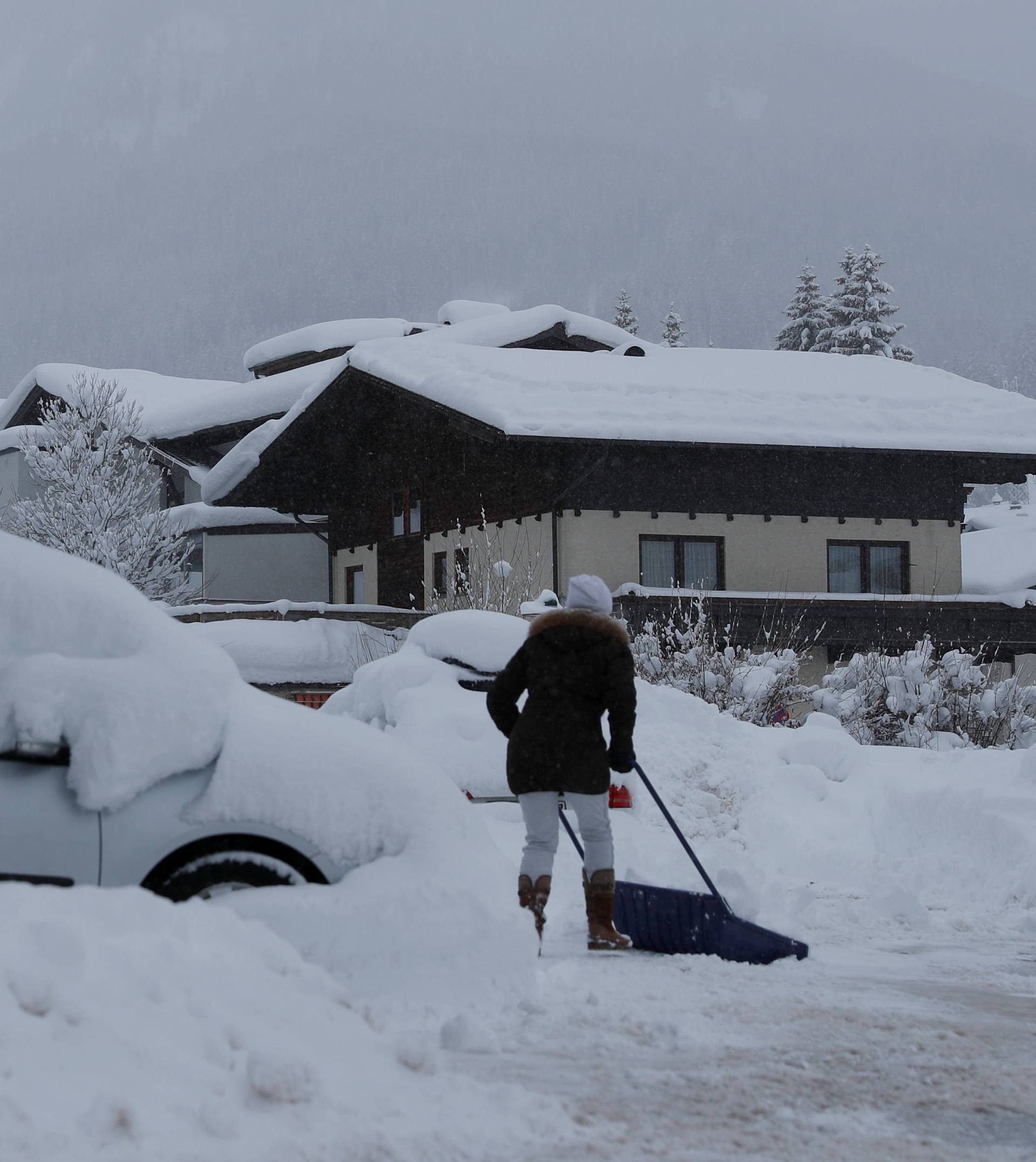 A woman shovels snow on a road after heavy snowfall in Flachau