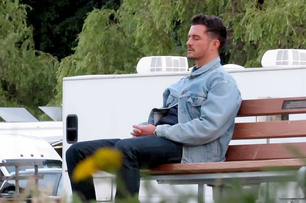 EXCLUSIVE: Orlando Bloom closes his eyes and gathers his thoughts on a park bench in Canada