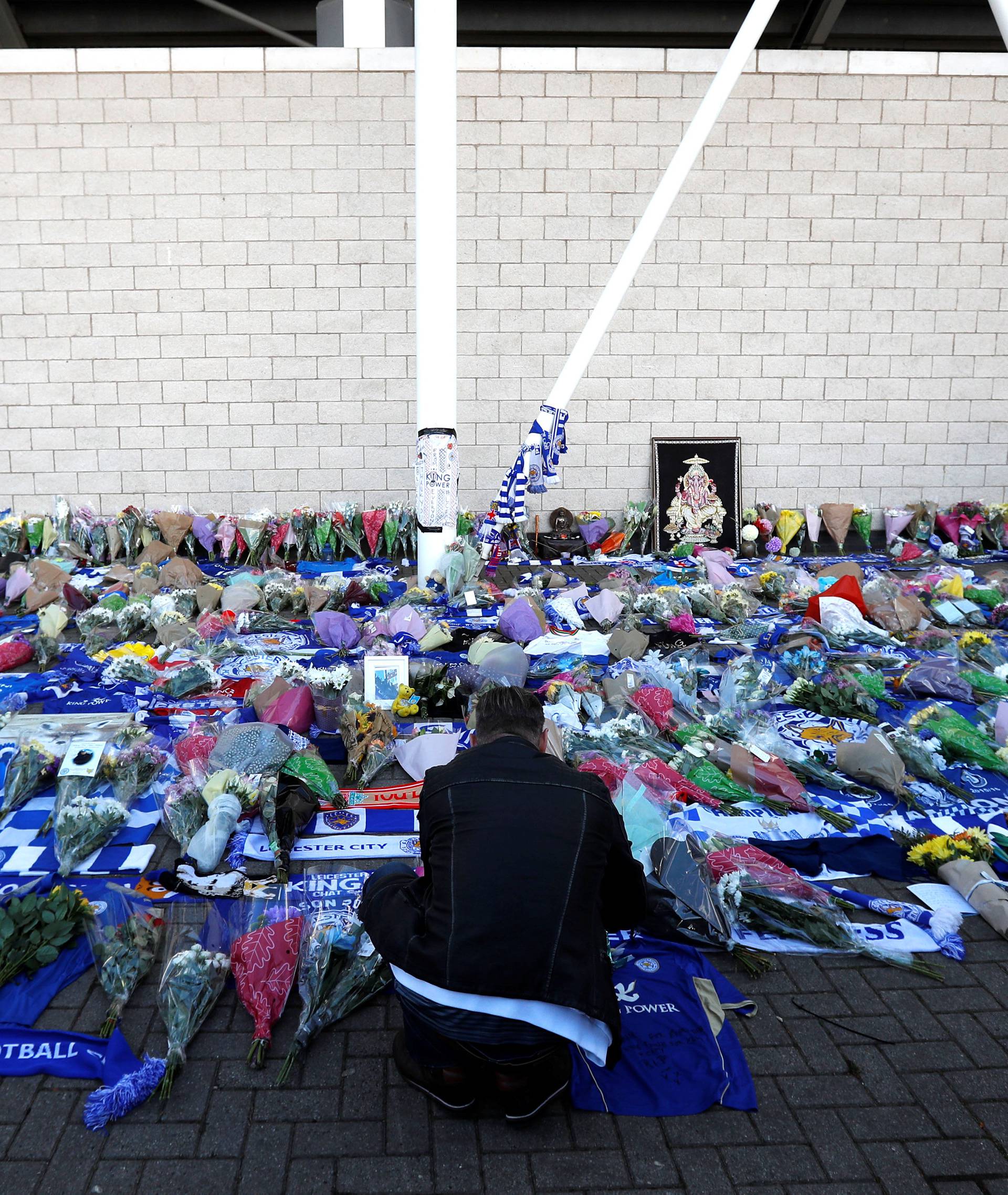 Leicester City football fans pay their respects outside the football stadium, after the helicopter of the club owner Thai businessman Vichai Srivaddhanaprabha crashed when leaving the ground on Saturday evening after the match, in Leicester