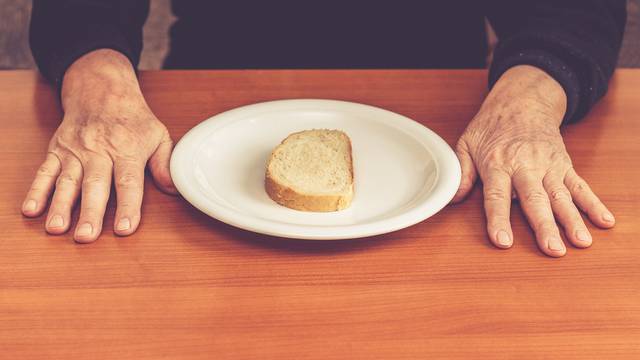 Old,Man's,Hands,On,Table,With,One,Slice,Of,Bread