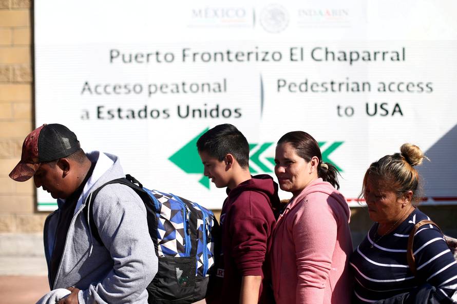 FILE PHOTO: Members of a caravan of migrants from Central America line up to enter the United States border and customs facility in Tijuana