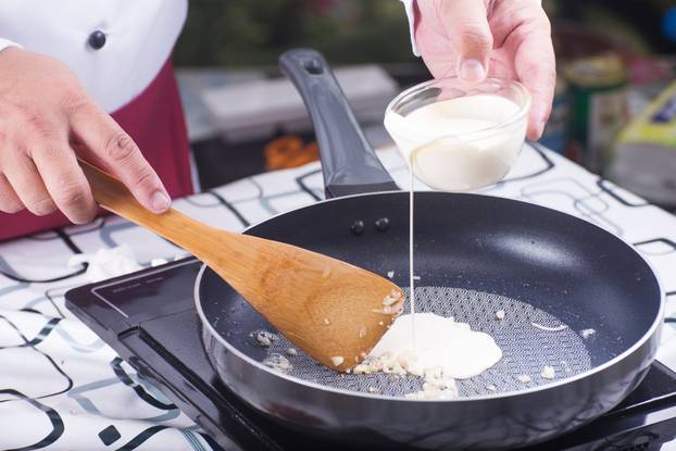 Chef pouring Whipping cream to the pan