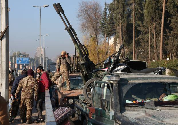 Rebel fighters stand next to a truck mounted with a weapon, in Damascus