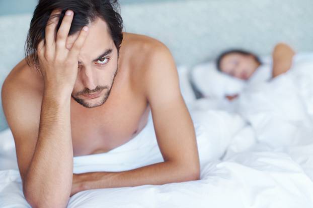 Are you serious. A young man sitting on the edge of his bed while his wife sleeps in the background.