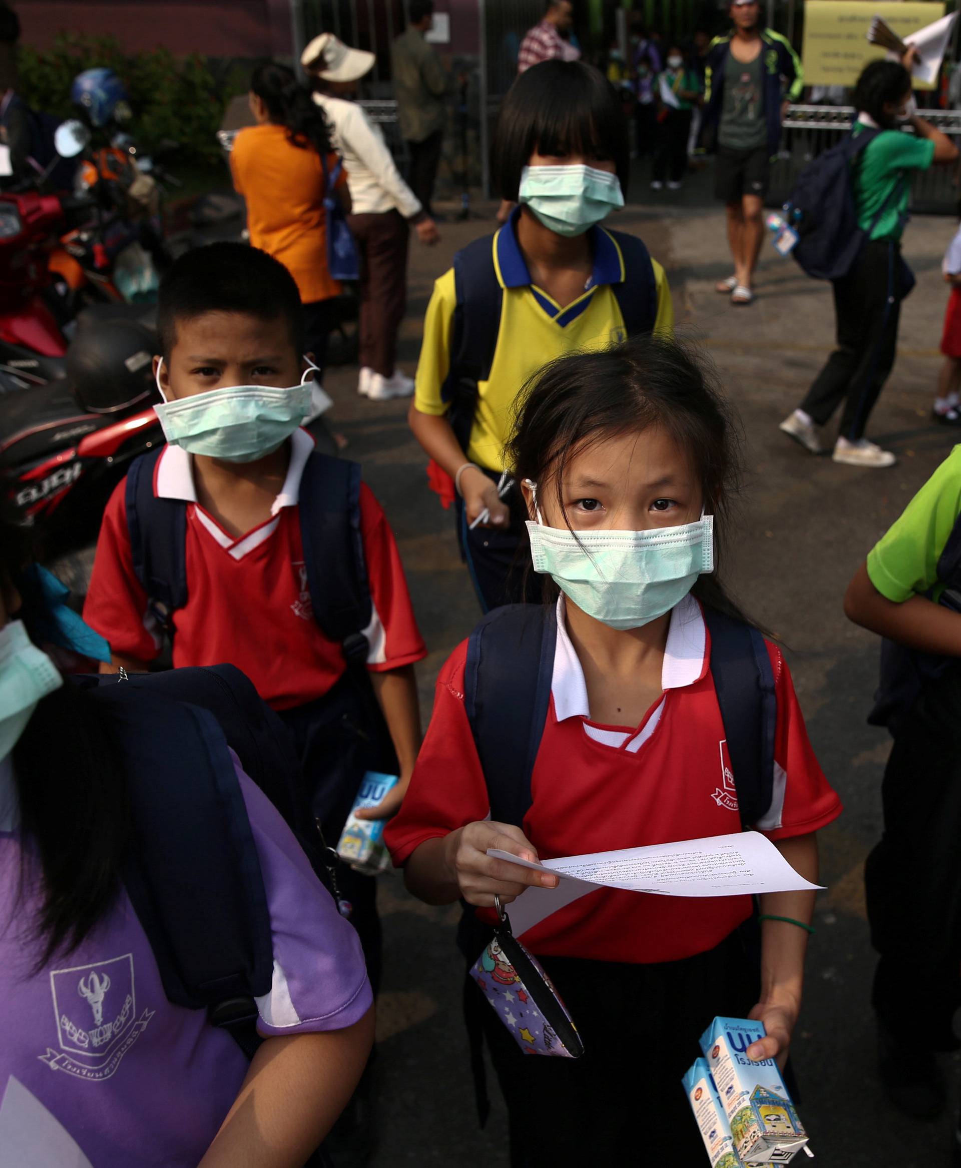 Students wear masks as they wait to be picked up during air pollution school closures in Bangkok