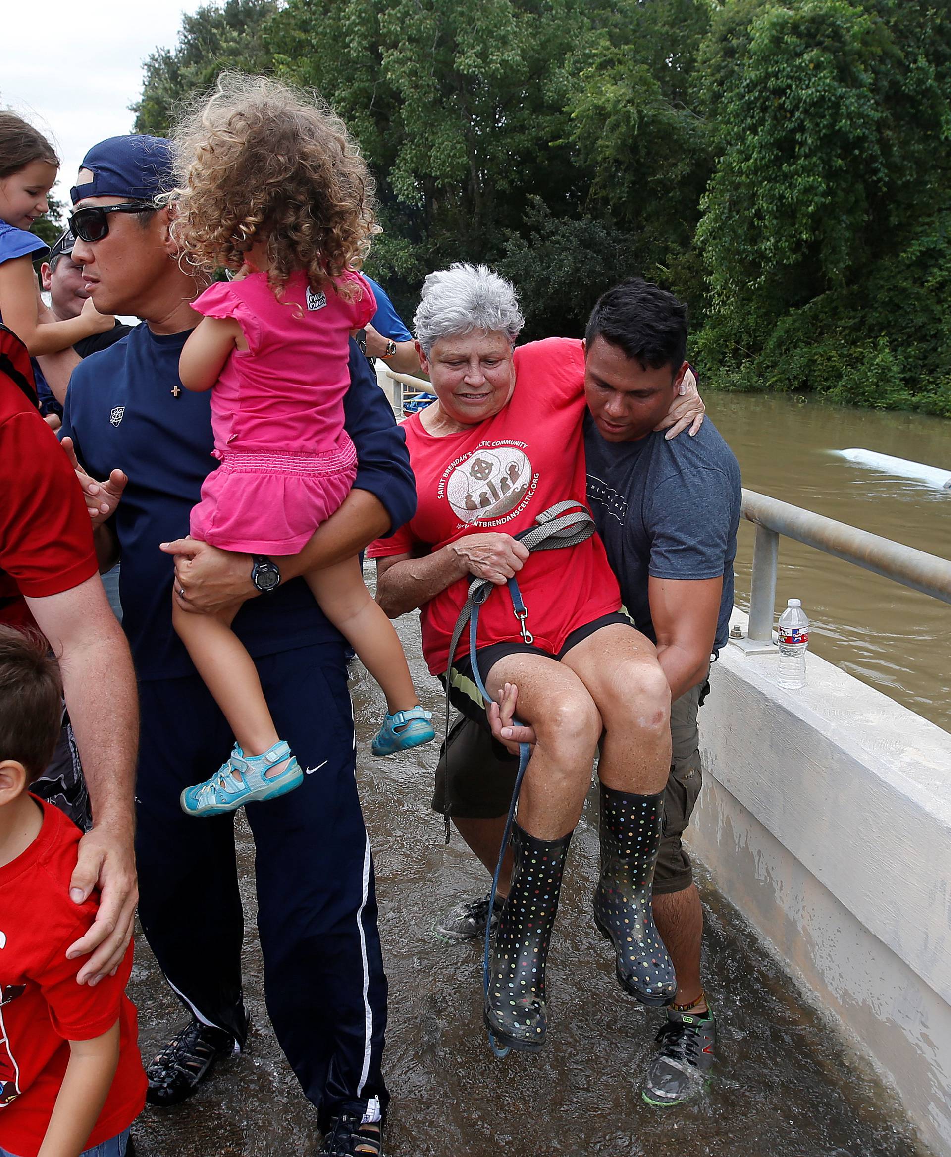 Volunteers help a woman from a rescue boat as it evacuates people from the rising waters of Buffalo Bayou following Hurricane Harvey in a neighborhood west of Houston
