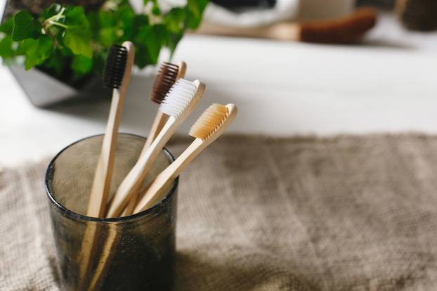 eco natural bamboo toothbrushes in glass on rustic background wi