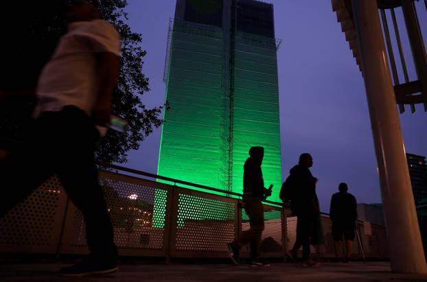 Grenfell Tower is seen covered and illuminated with green light one year after the tower fire in London