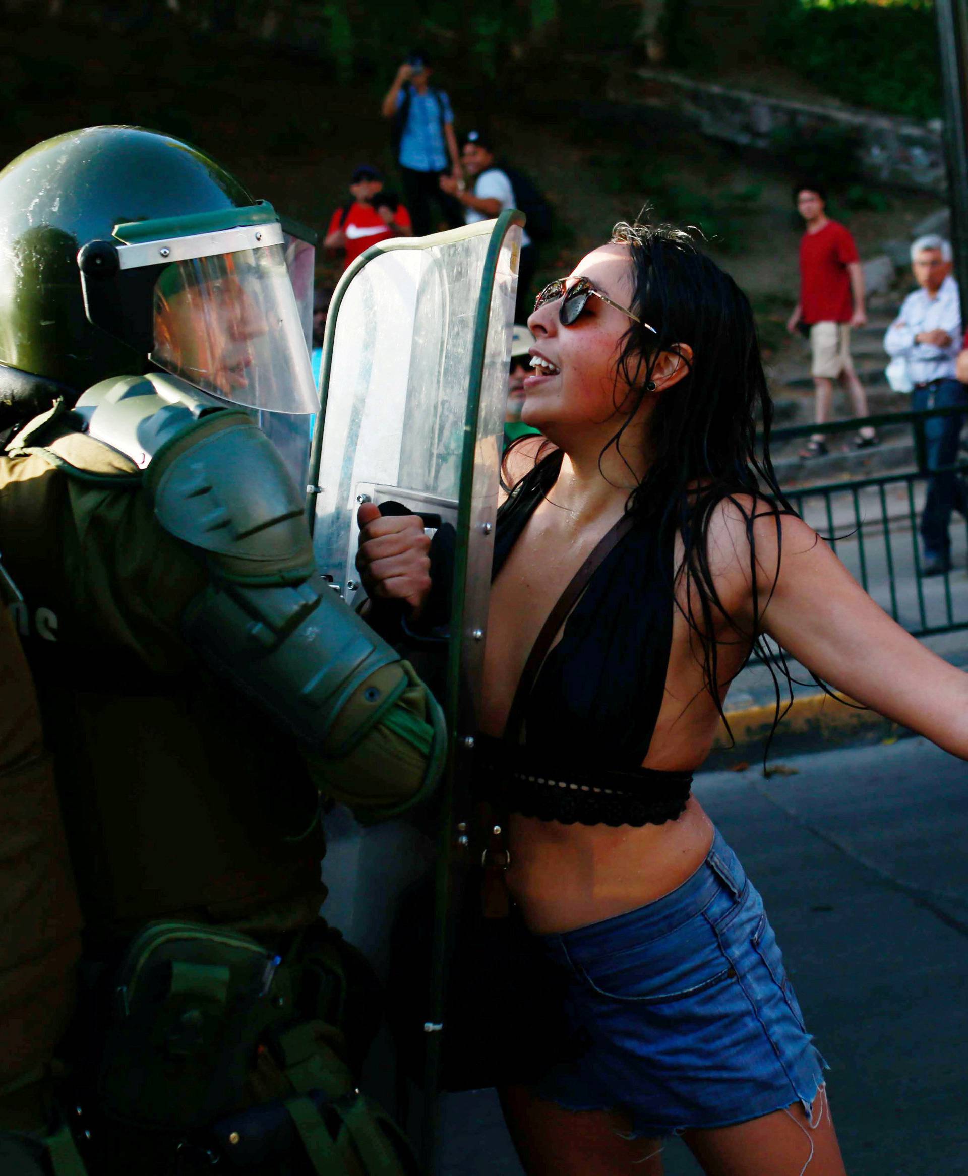 A demonstrator confronts riot police during a rally in defense of the nationalization of lithium reserves in Santiago
