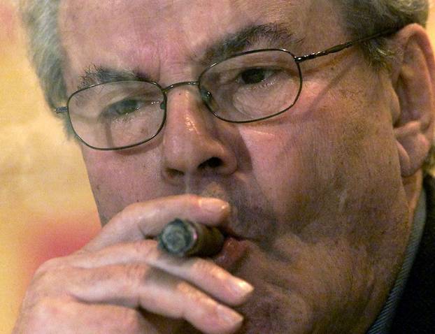 FILE PHOTO: Czech film director Milos Forman smokes a cigar as he listens to journalists