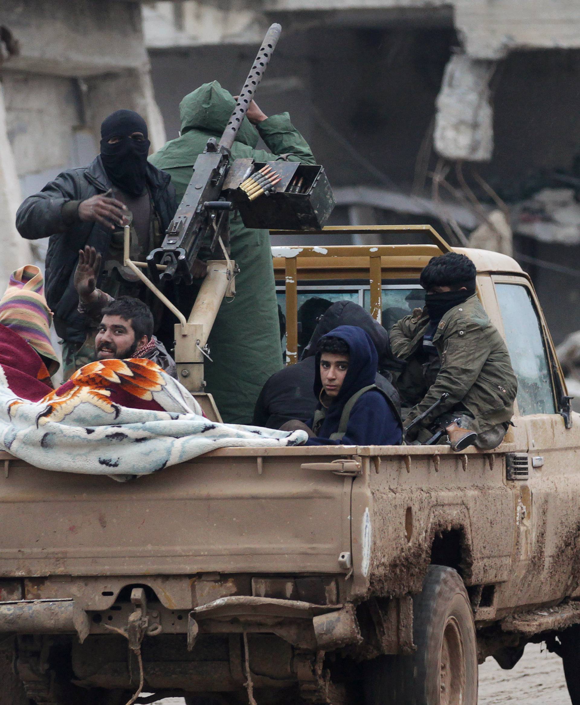 Rebel fighters ride on a pick-up truck in the northern Syrian rebel-held town of al-Rai