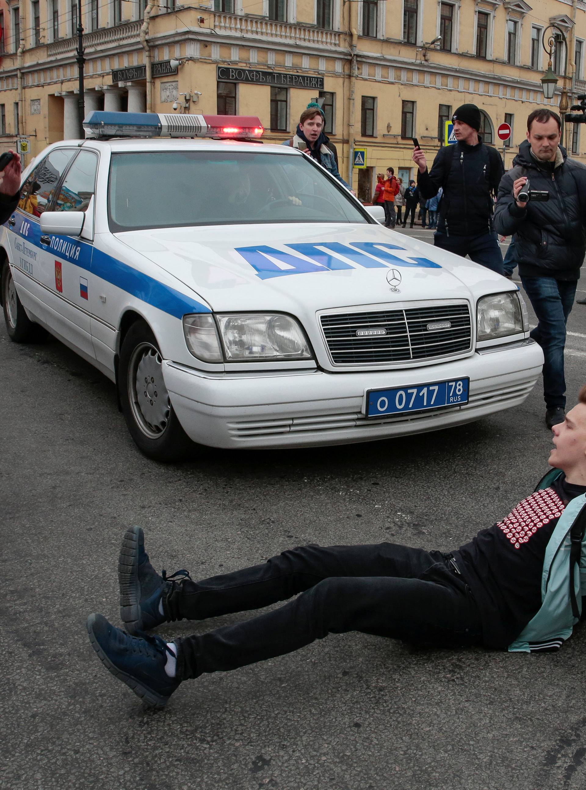 An opposition supporter tries to block a police car during a protest ahead of President Vladimir Putin's inauguration ceremony, Saint Petersburg