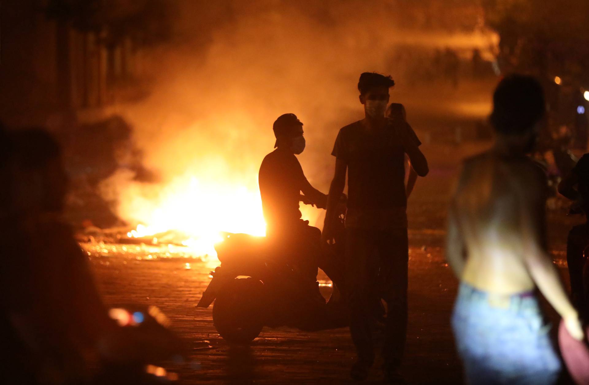 Demonstrators are pictured near burning fire during a protest near parliament in Beirut