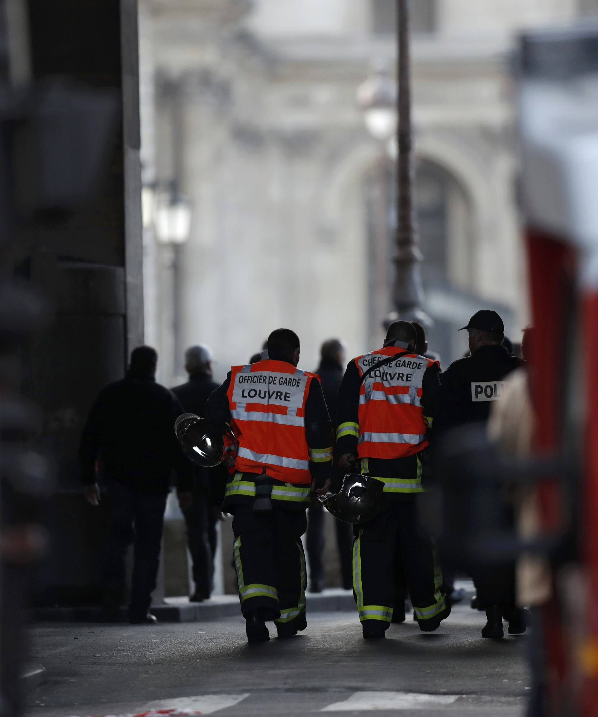 French firefighters and police are seen at the site near the Louvre Pyramid in Paris