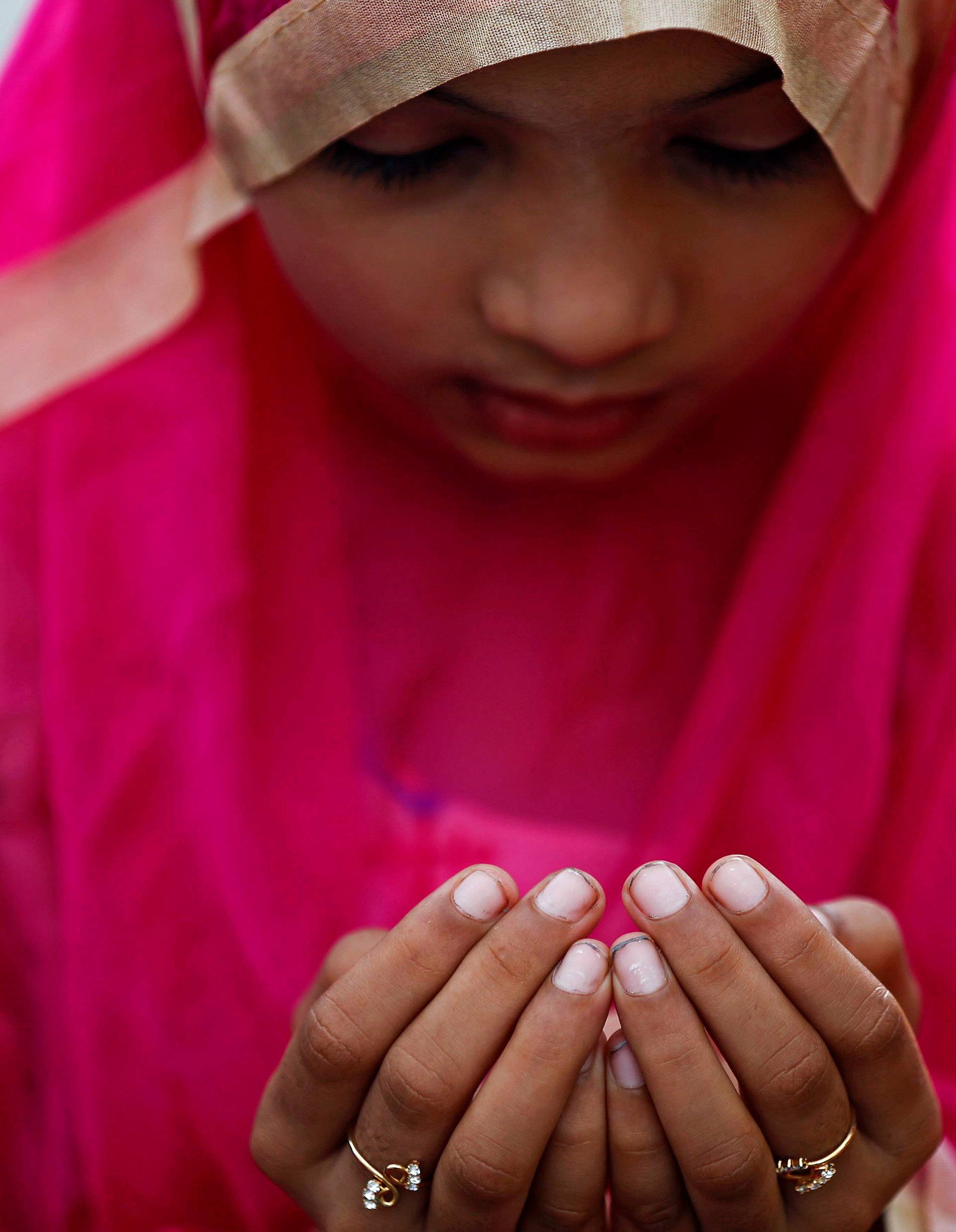 A girl offers Eid al-Adha prayers on a street outside a railway station in Mumbai