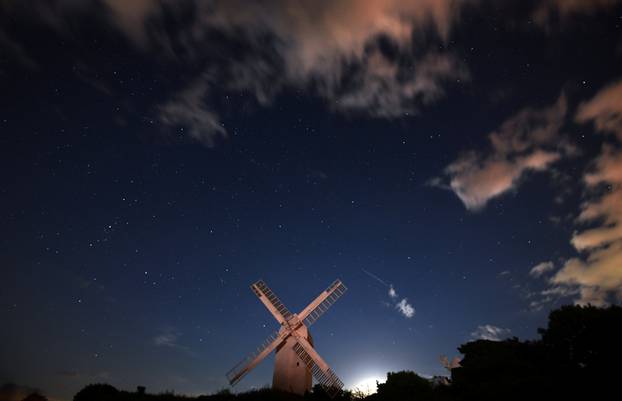 A meteor streaks past stars in the night sky above the Jill Windmill, during the Perseid meteor shower in Brighton
