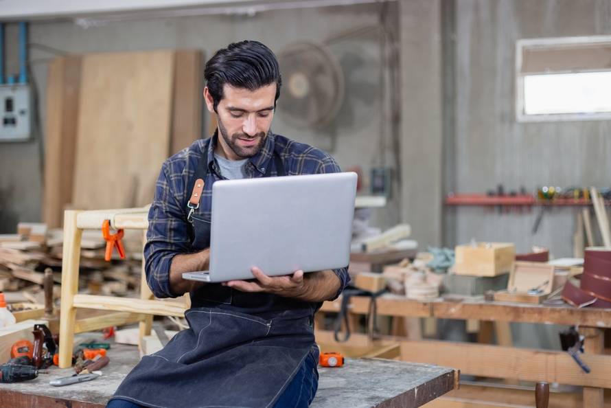 Young,Carpenter,Caucasian,Man,With,Laptop,Make,Drawing,On,Wood