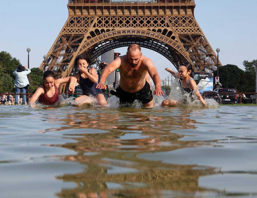 People cool off in the Trocadero Fountain next to the Eiffel Tower in Paris