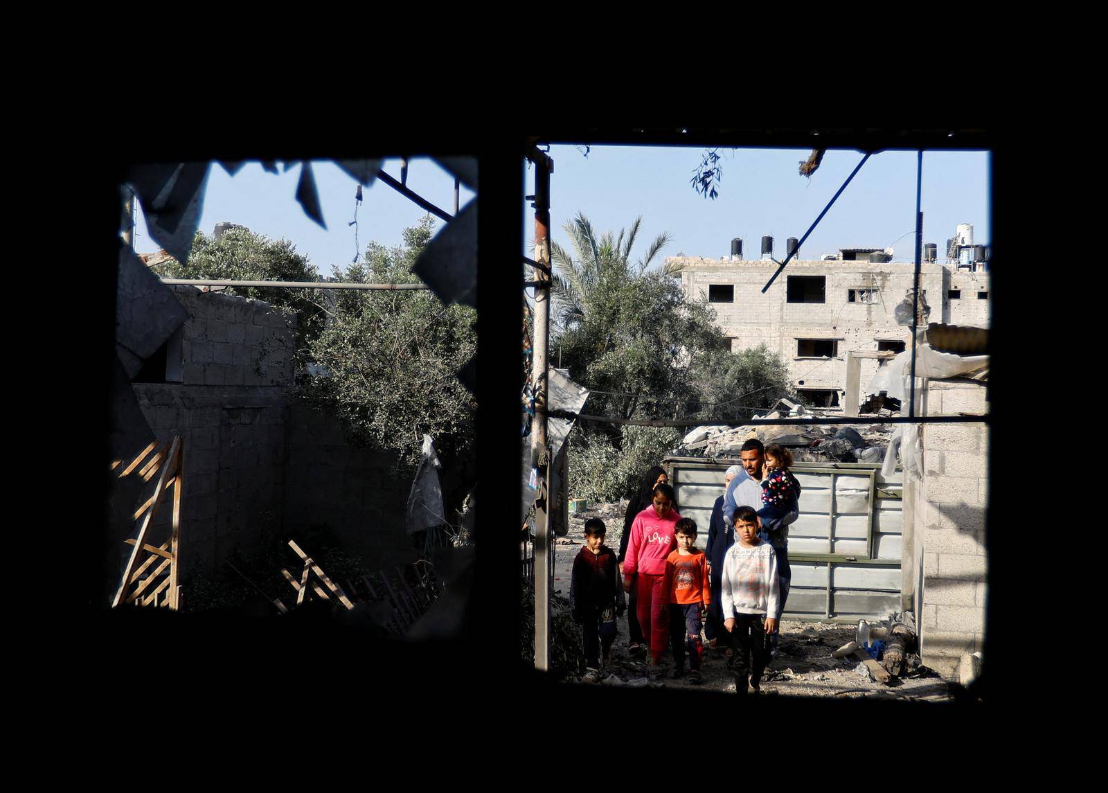 People look at a building, which was destroyed in an Israeli strike during Israel-Gaza fighting, after a ceasefire was agreed between Palestinian factions and Israel