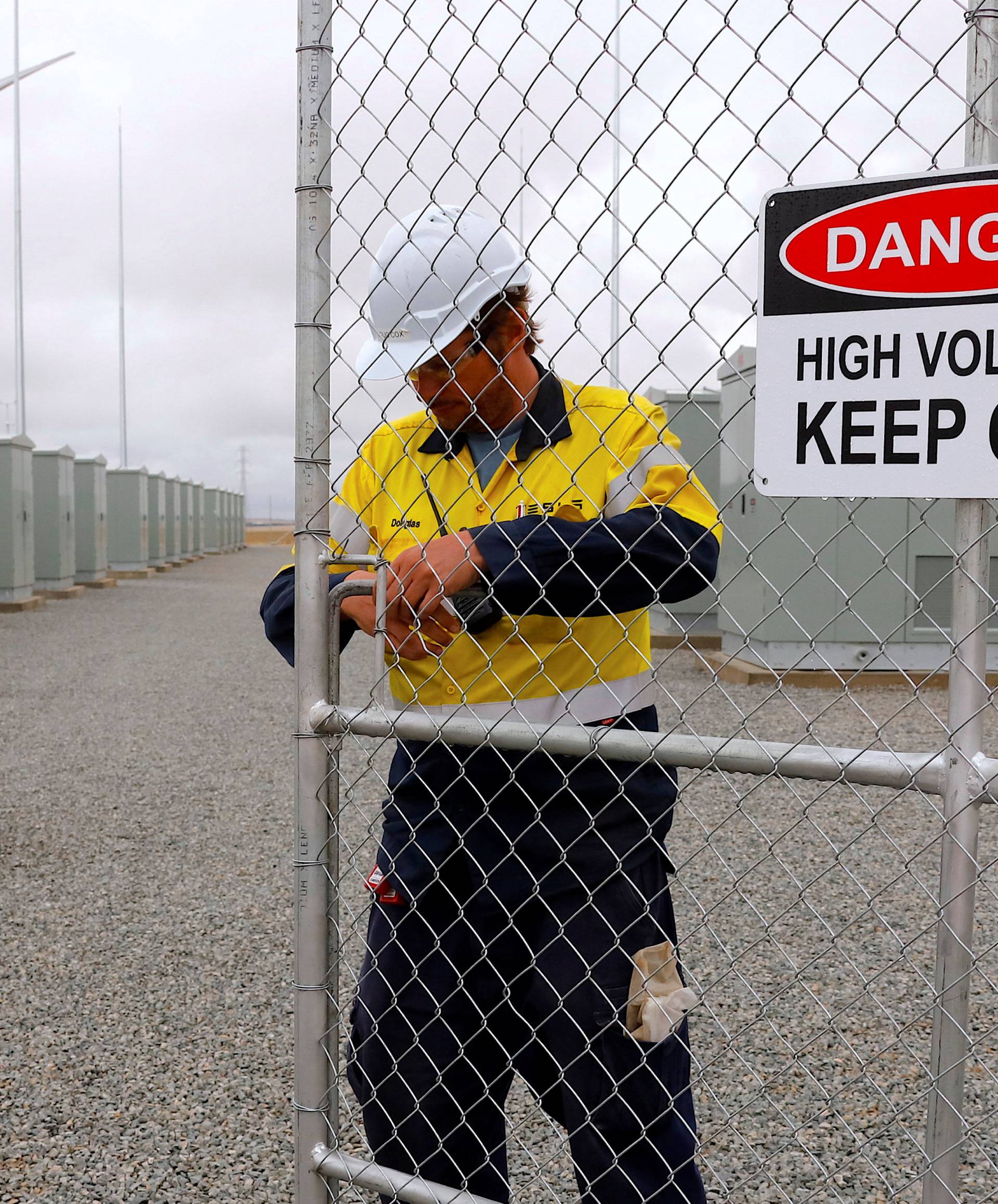  A worker checks the main gate for the compound housing the Hornsdale Power Reserve, featuring the world's largest lithium ion battery made by Tesla, during the official launch near the South Australian town of Jamestown