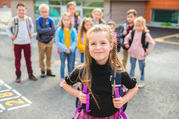 A schoolgirl standing with other student on the back