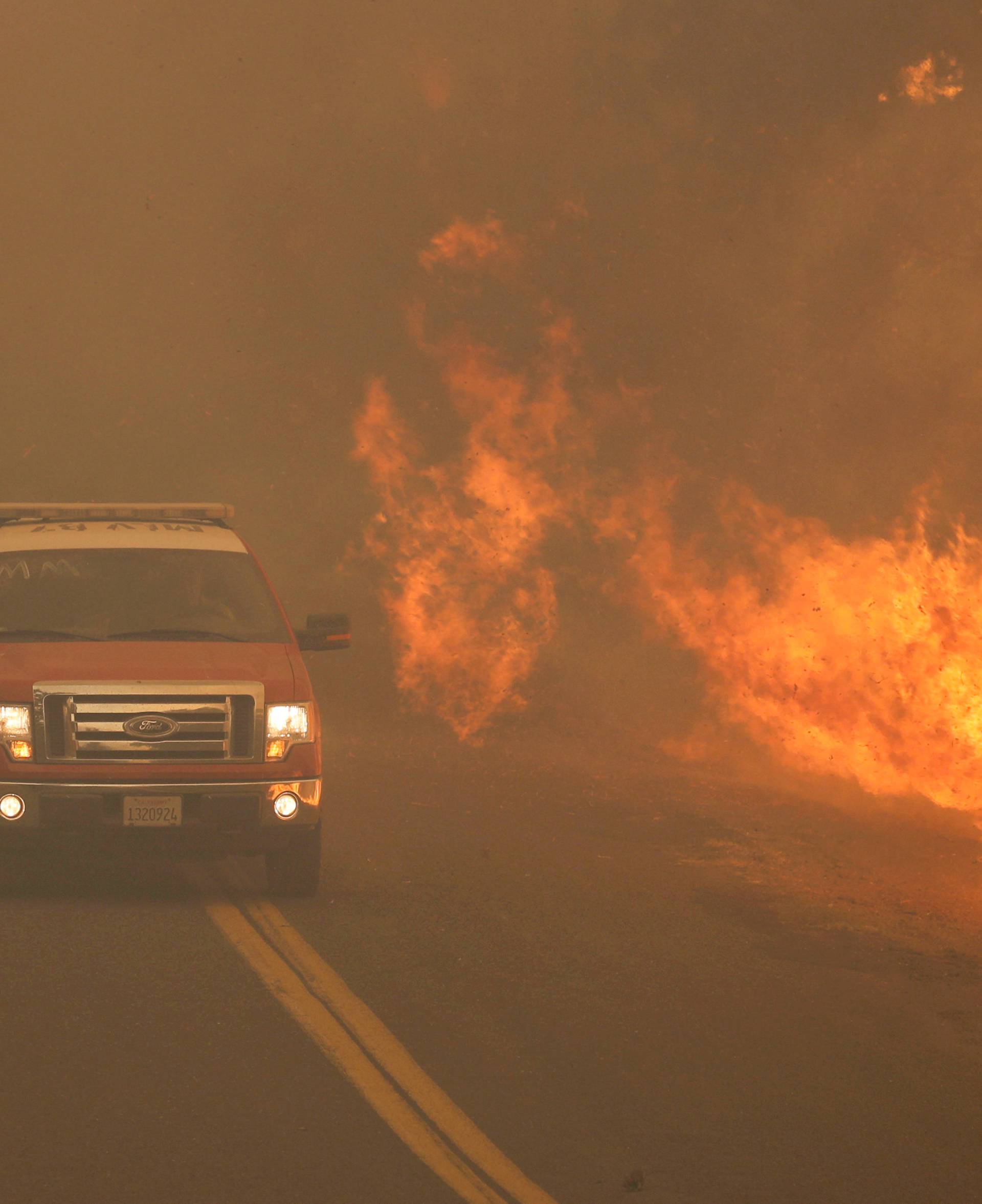 FILE PHOTO: A firetruck rushes past flames that overran a road at the River Fire in Lakeport