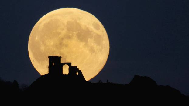 People watch as the Supermoon, known as the Hunter’s moon rises over Mow Cop castle in Mow Cop