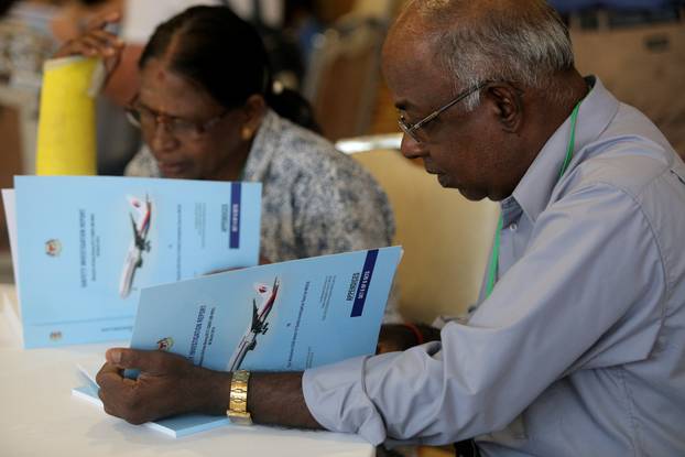 Family members read MH370 briefing reports before a closed door meeting in Putrajaya