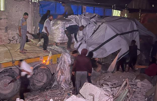 Palestinian workers unload an aid truck, in Khan Younis