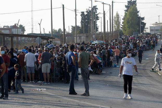 Refugees and migrants, from the destroyed Moria camp, line up to enter a new temporary camp, on the island of Lesbos