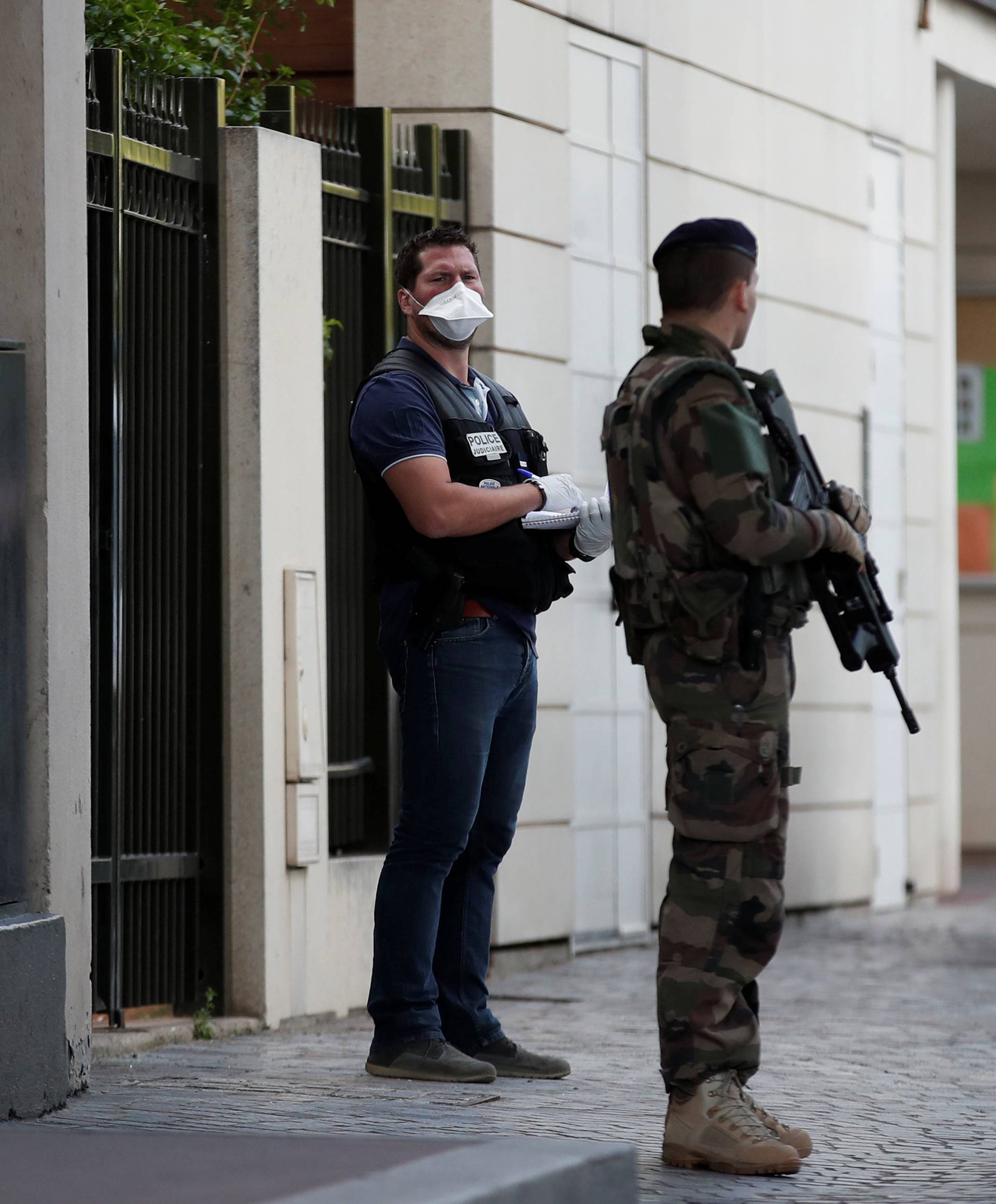 A police investigator and an armed soldier work near the scene where French soliders were hit and injured by a vehicle in the western Paris suburb of Levallois-Perret