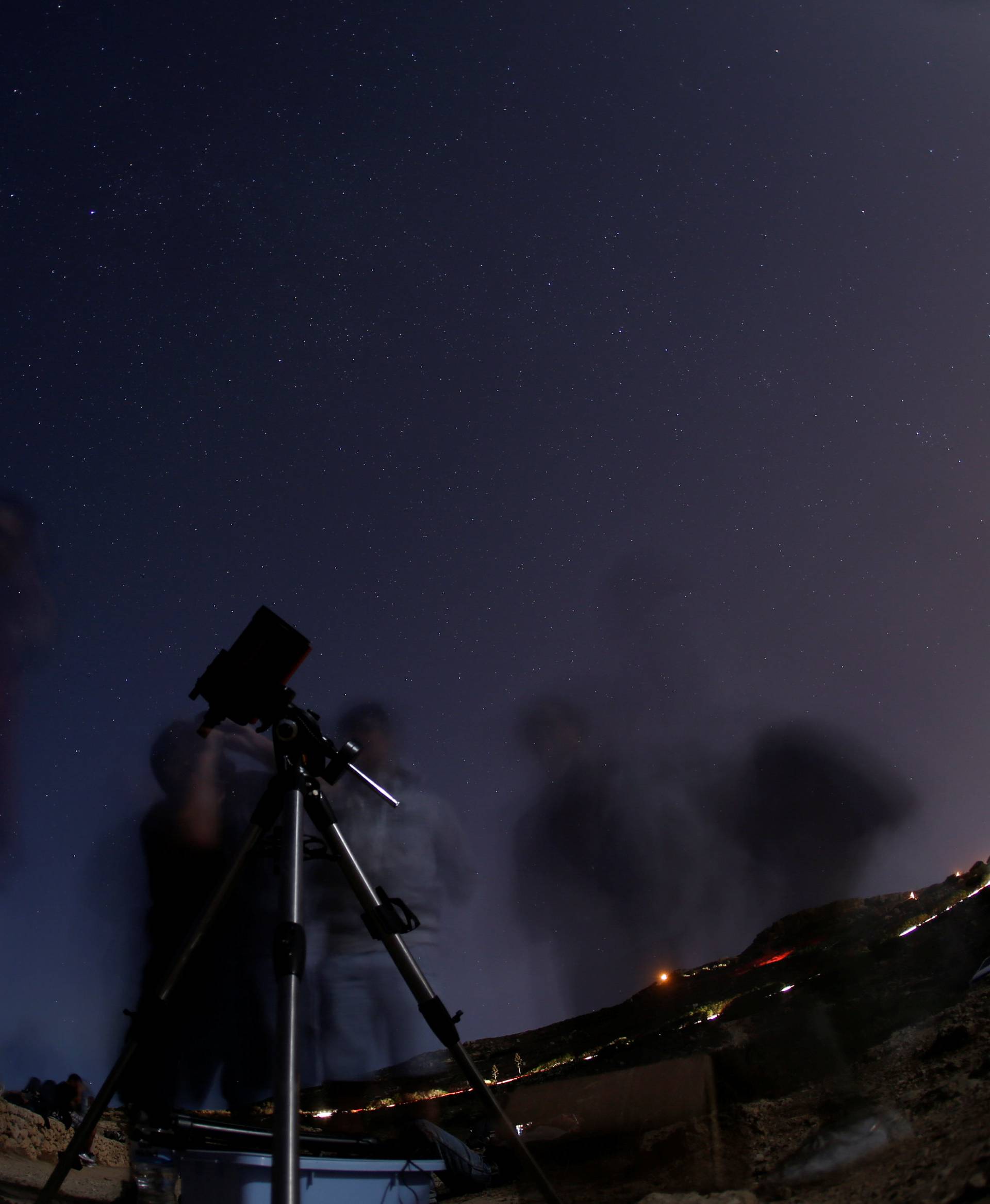 A man looks at the moon through a telescope during the Perseid meteor shower at Migra l-Ferha, outside the town of Rabat