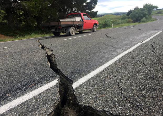 A truck drives over the fractured road caused by an earthquake south of the New Zealand town of Ward on the South Island