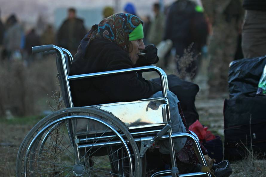 An evacuee from rebel-held east Aleppo, eats as she sits in a wheelchair upon her arrival with others to the town of al-Rashideen