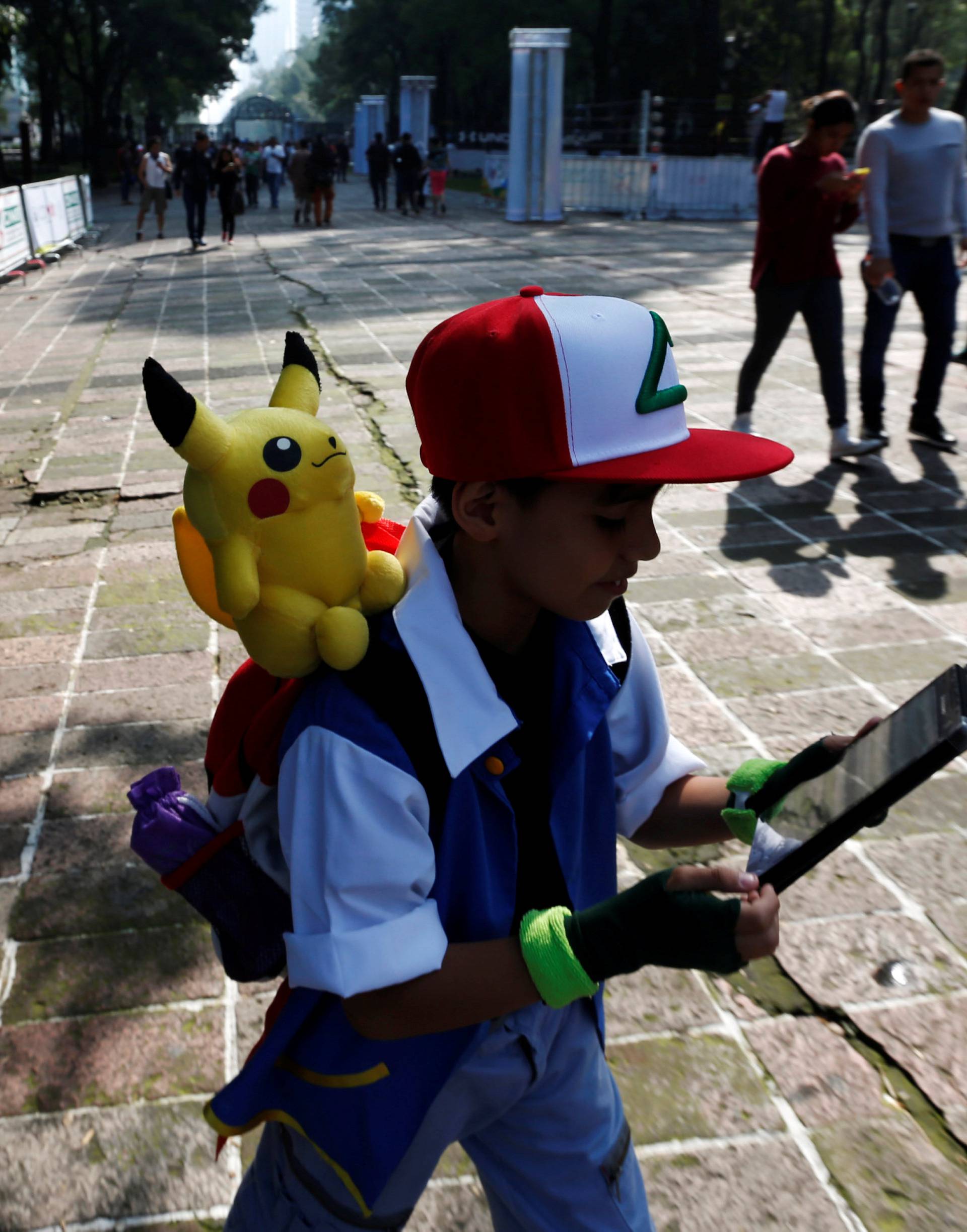 A child carries a Pokemon character, Pikachu, on his shoulder as he plays Pokemon Go during a gathering to celebrate "Pokemon Day" in Mexico City