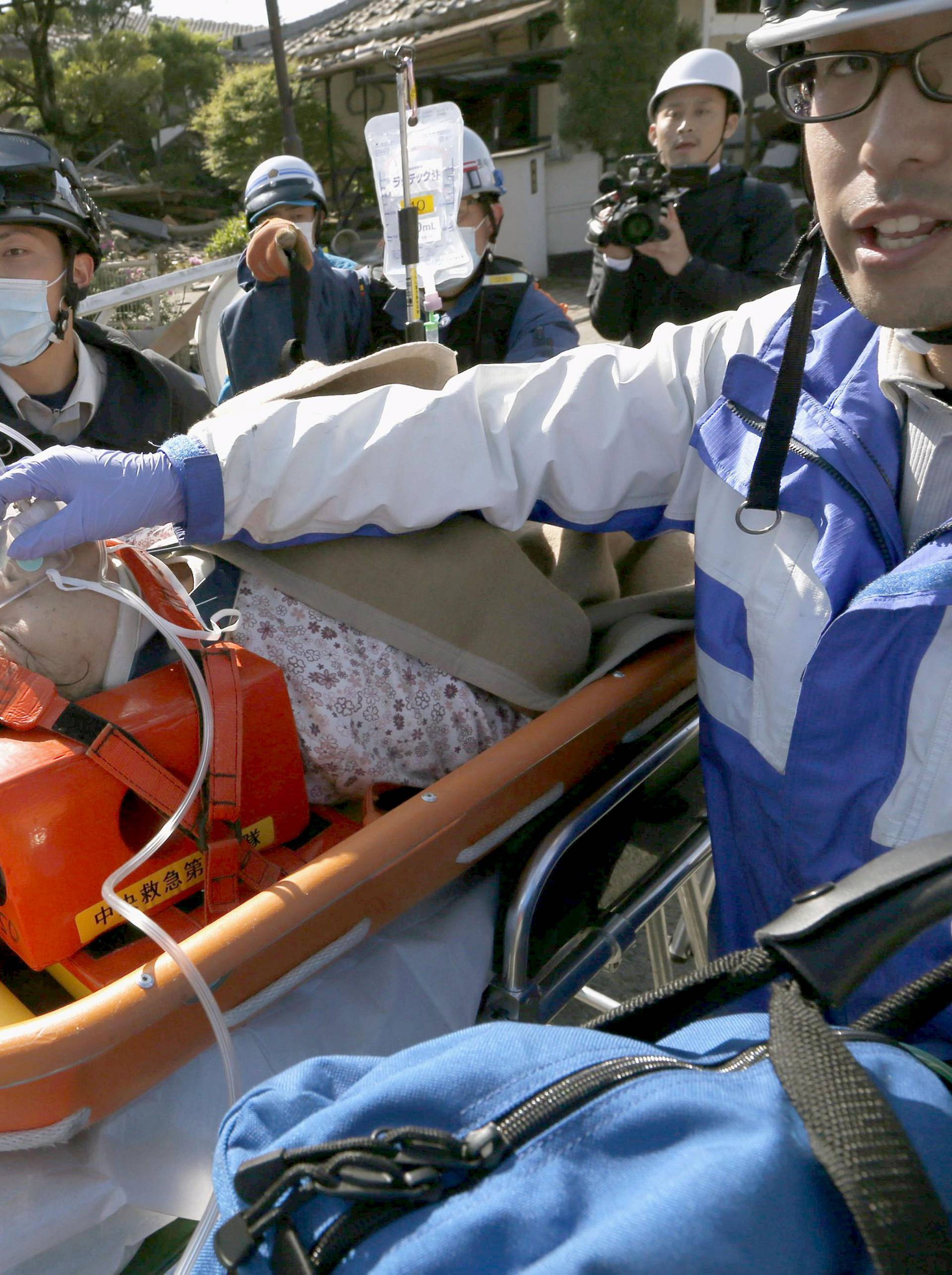A woman is carried away by rescue workers after being rescued from her collapsed home caused by an earthquake in Mashiki town, Kumamoto prefecture, southern Japan