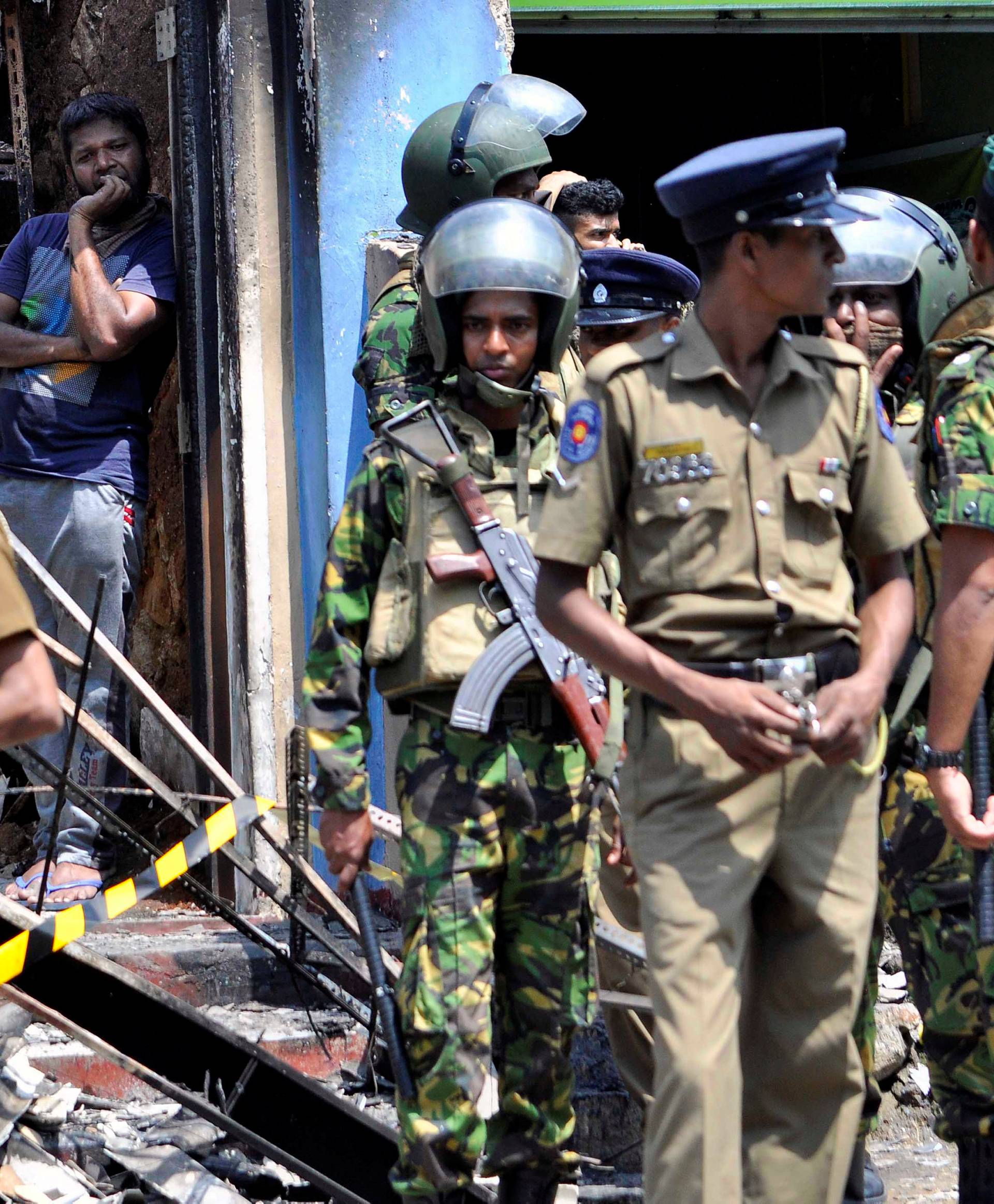 Sri Lanka's Special Task Force and Police officers stand guard near a burnt house after a clash between  two communities in Digana, central district of Kandy