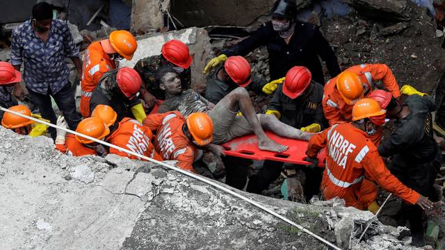 National Disaster Response Force (NDRF) officials rescue a man from the debris after a three-storey residential building collapsed in Bhiwandi on the outskirts of Mumbai, India