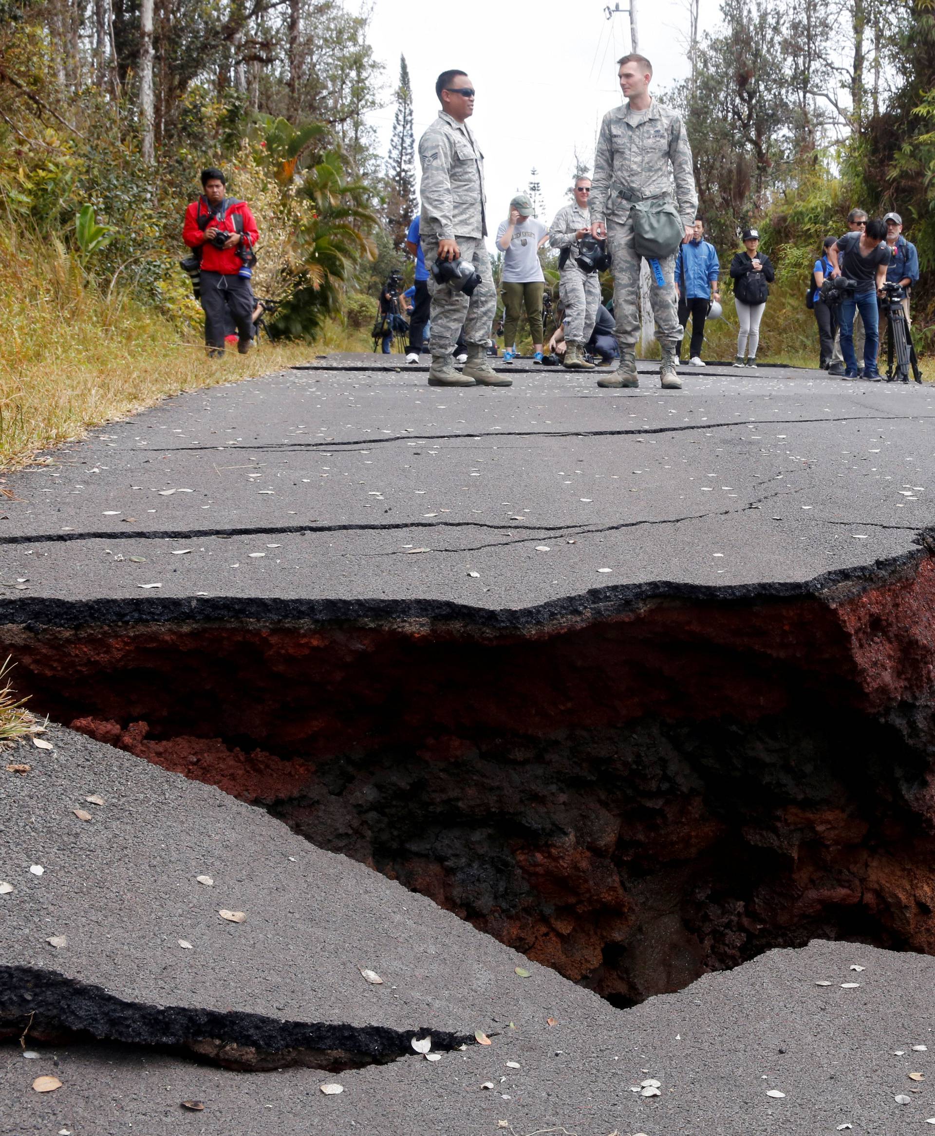 Journalists and soldiers of the Hawaii National Guard document road damage in Leilani Estates during ongoing eruptions of the Kilauea Volcano in Hawaii