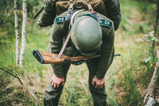 Tired Unidentified Re-enactor Dressed As German Wehrmacht Infantry Soldier In World War II Trying To Catch His Breath At Rest In Forest In Summer Day.