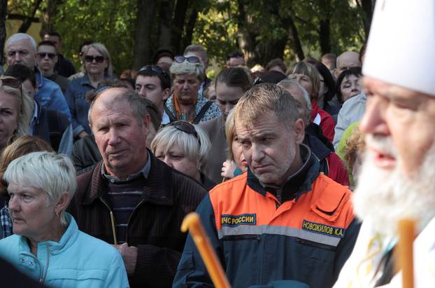 A priest conducts a memorial service for victims of an attack on a college in Kerch